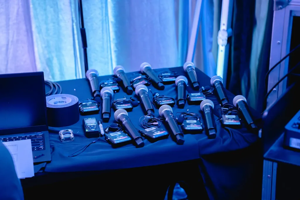 Wireless microphones and audio equipment organized backstage before a corporate event, demonstrating the preparation and planning required for a no-surprises event production experience.