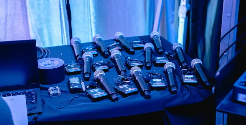 Wireless microphones and audio equipment organized backstage before a corporate event, demonstrating the preparation and planning required for a no-surprises event production experience.